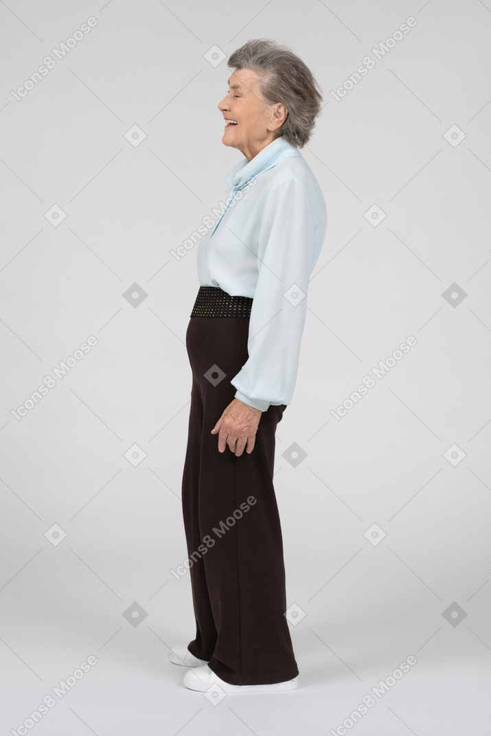 Vista lateral de una anciana riendo a carcajadas