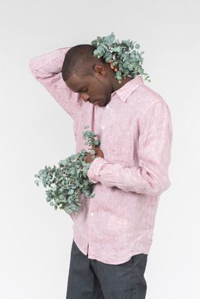 Good looking young man holding green branches