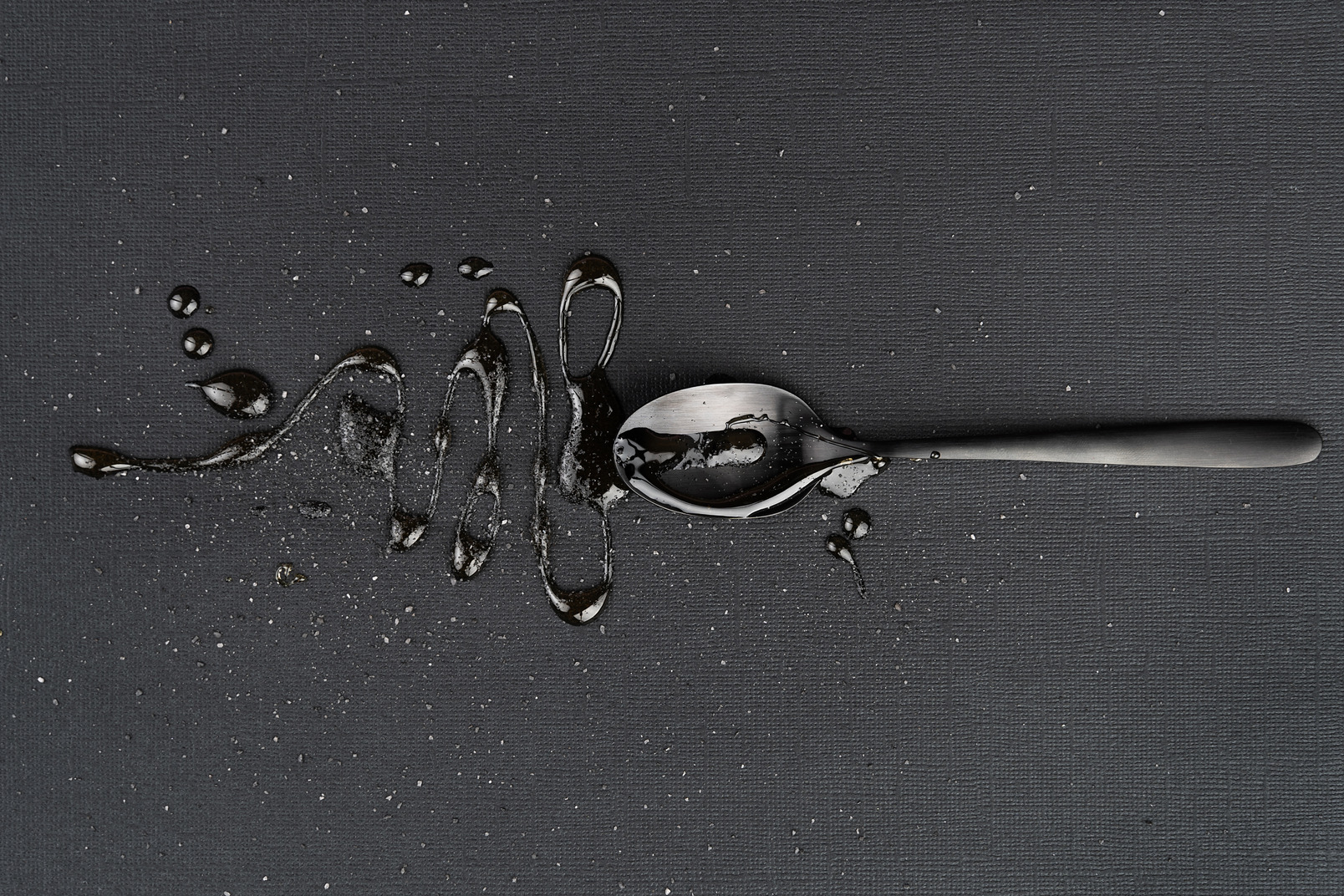 Metal tea spoon with liquid on the black