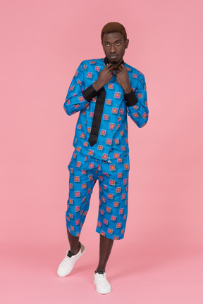 Black man in blue pajamas standing on the pink background