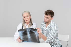 Aged female doctor and a patient looking at x-ray photograph together