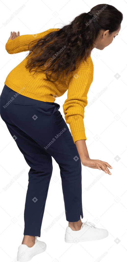 Vue arrière d'une fille en vêtements décontractés posant sur une jambe avec les bras tendus
