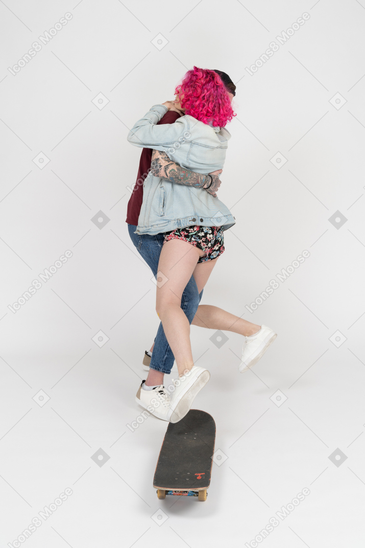 Pink haired girl falling down from a skateboard to her boyfriend`s arms