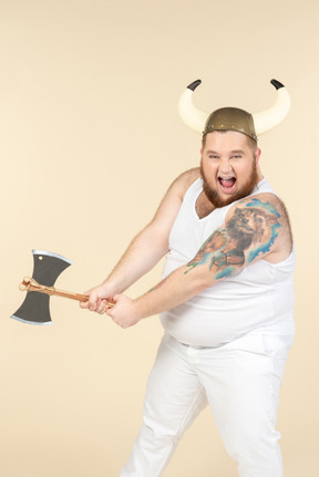 An emotional plus-sized man in white with a horned helmet on his head, holding a double-bladed axe