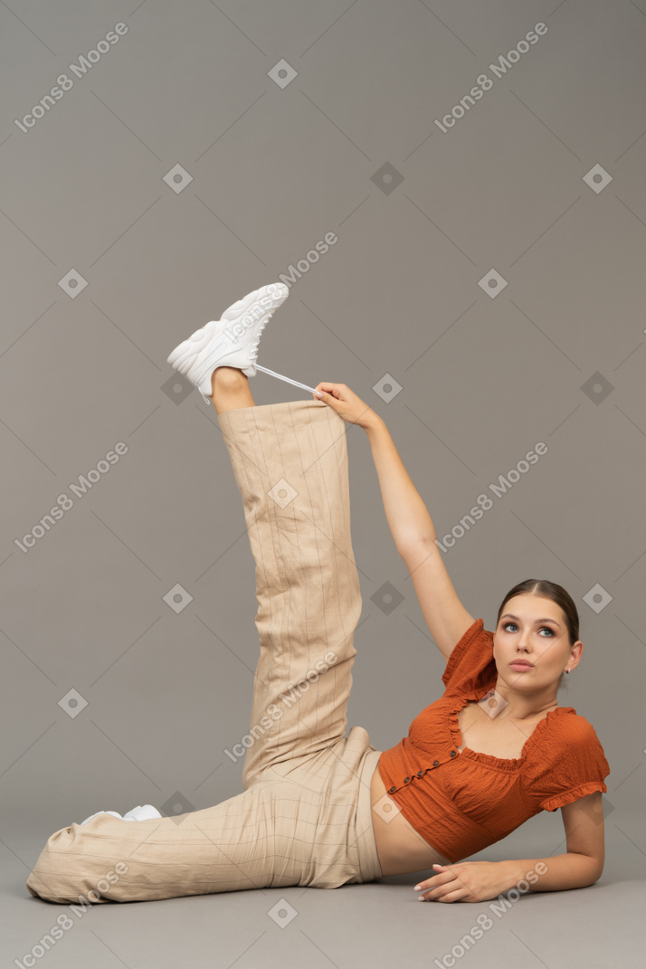 Молодая женщина протягивает ногу и держит шнурки