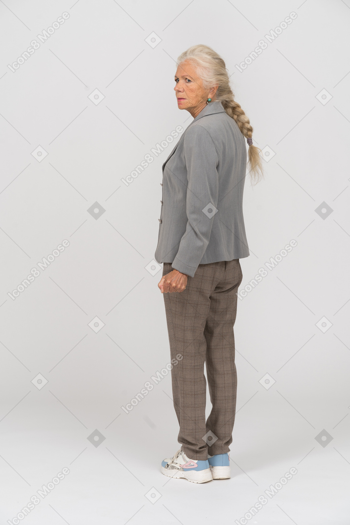 Vista trasera de una anciana en traje mirando algo
