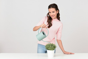 Привлекательная молодая женщина поливает комнатное растение