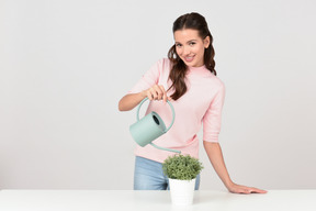 Jolie jeune femme arroser une plante d'intérieur