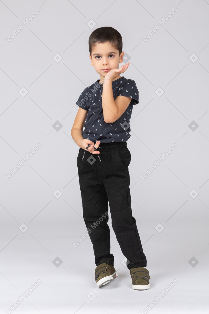 Front view of a cute boy posing with hand on chin and looking at camera
