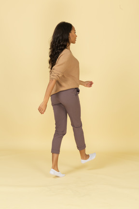 浅黒い肌の歩く若い女性の4分の3の背面図