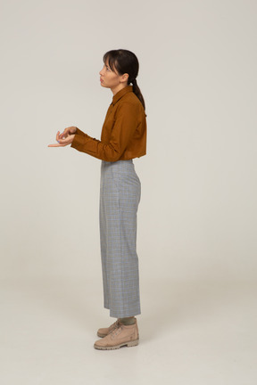 Vista laterale di una giovane donna asiatica che conta in calzoni e camicetta