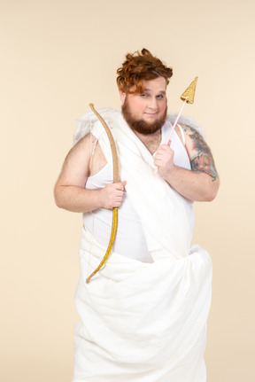 Cunning looking young man dressed as a cupid holding bow and arrow