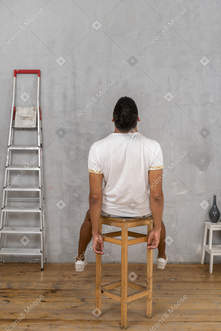 Back view of young man sitting on chair