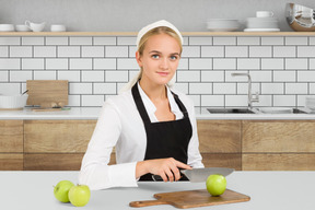 A woman in an apron cutting apples on a cutting board