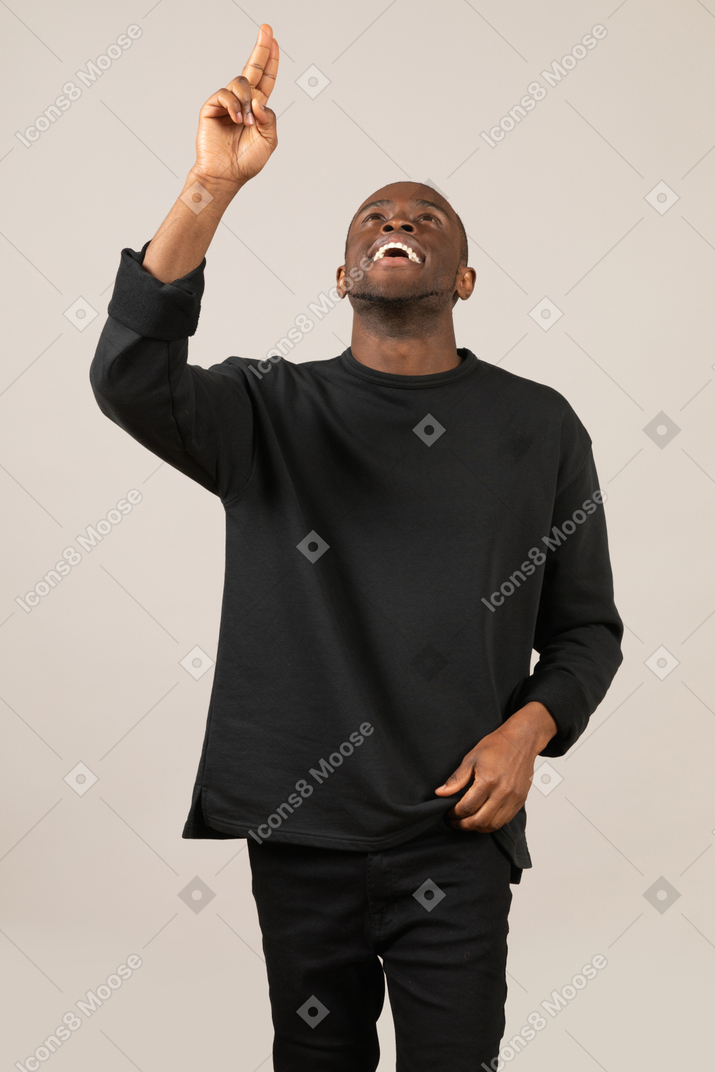 Happy young man pointing up with raised head