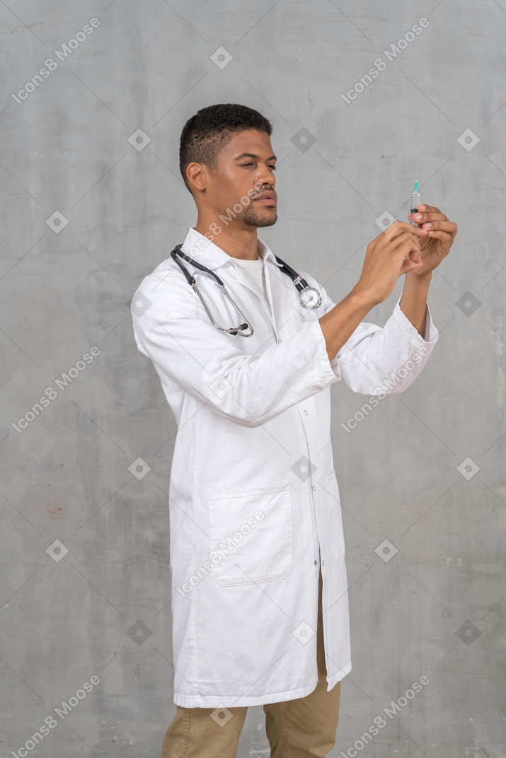 Doctor de sexo masculino que prepara una jeringuilla