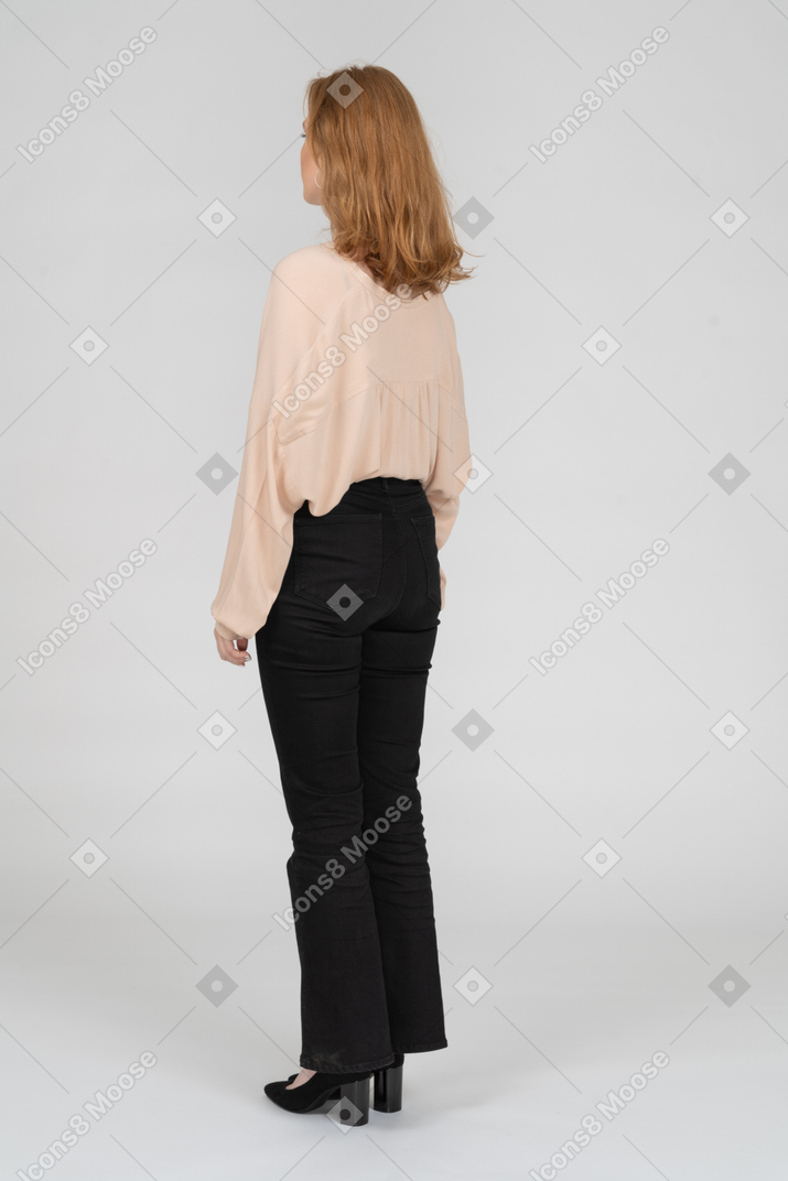 Three quarter back view of young woman standing