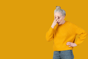 A woman in a yellow sweater is covering her face
