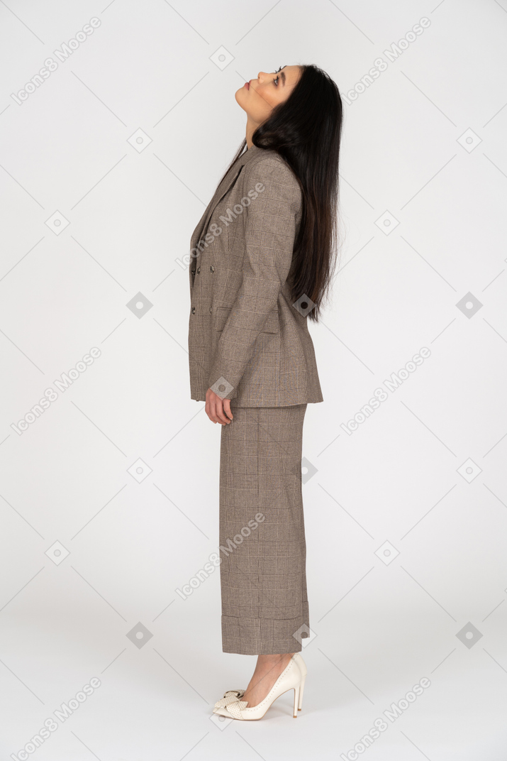 Vista lateral de uma jovem de terno marrom levantando a cabeça
