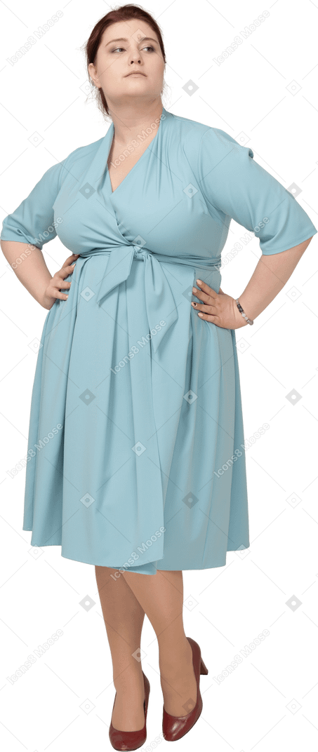 Vista frontal de uma mulher de vestido azul posando com as mãos na cintura
