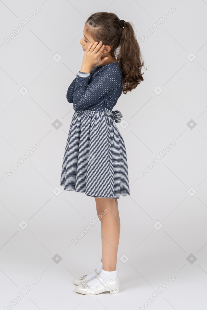 Sleepy girl standing with hands folded under cheek