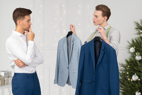 A man is trying to decide which suit to wear