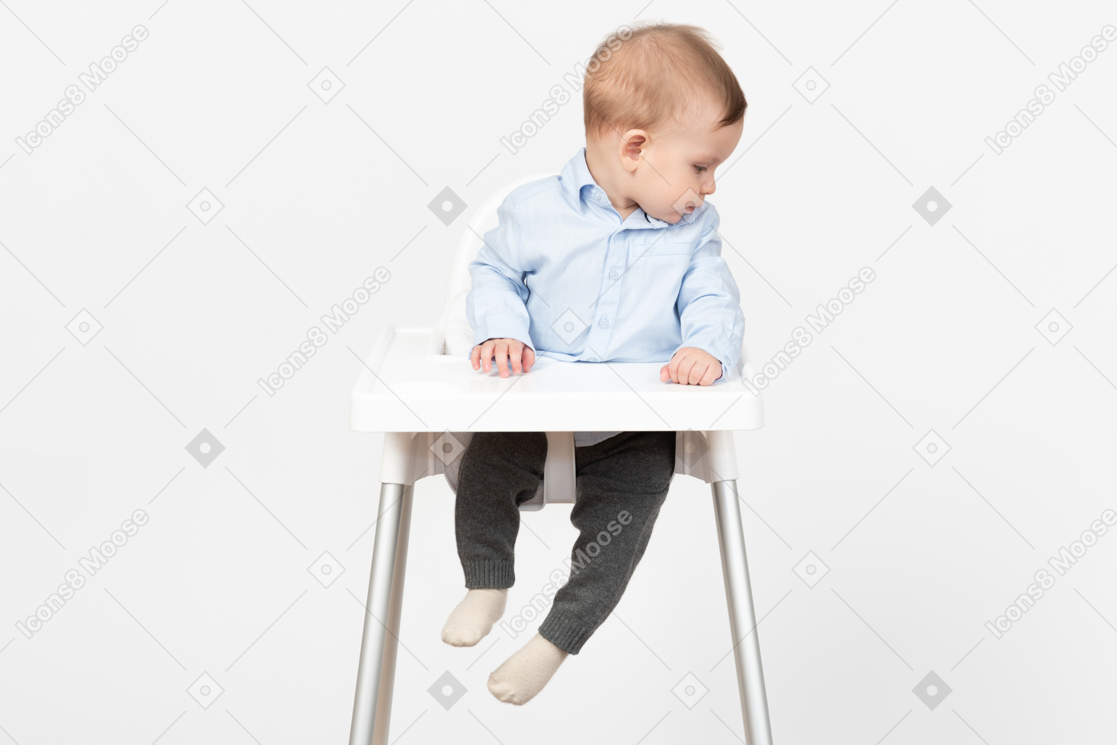 Adorable baby boy sitting in highchair and looking aside