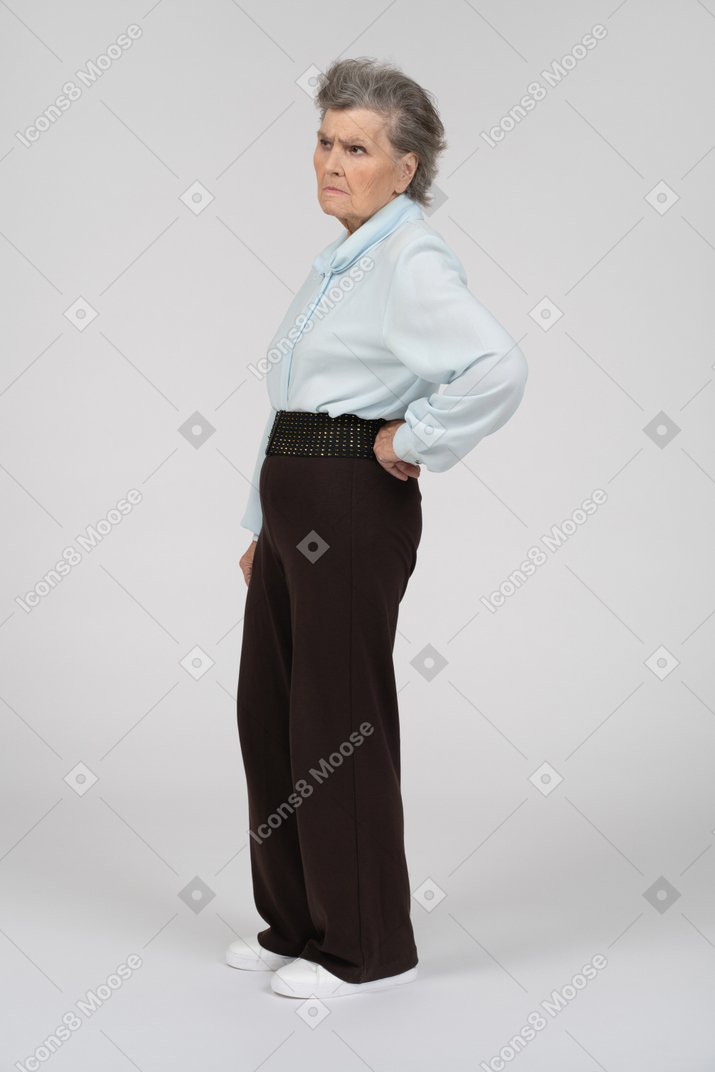 Vista laterale di una donna anziana accigliata con una mano sull'anca