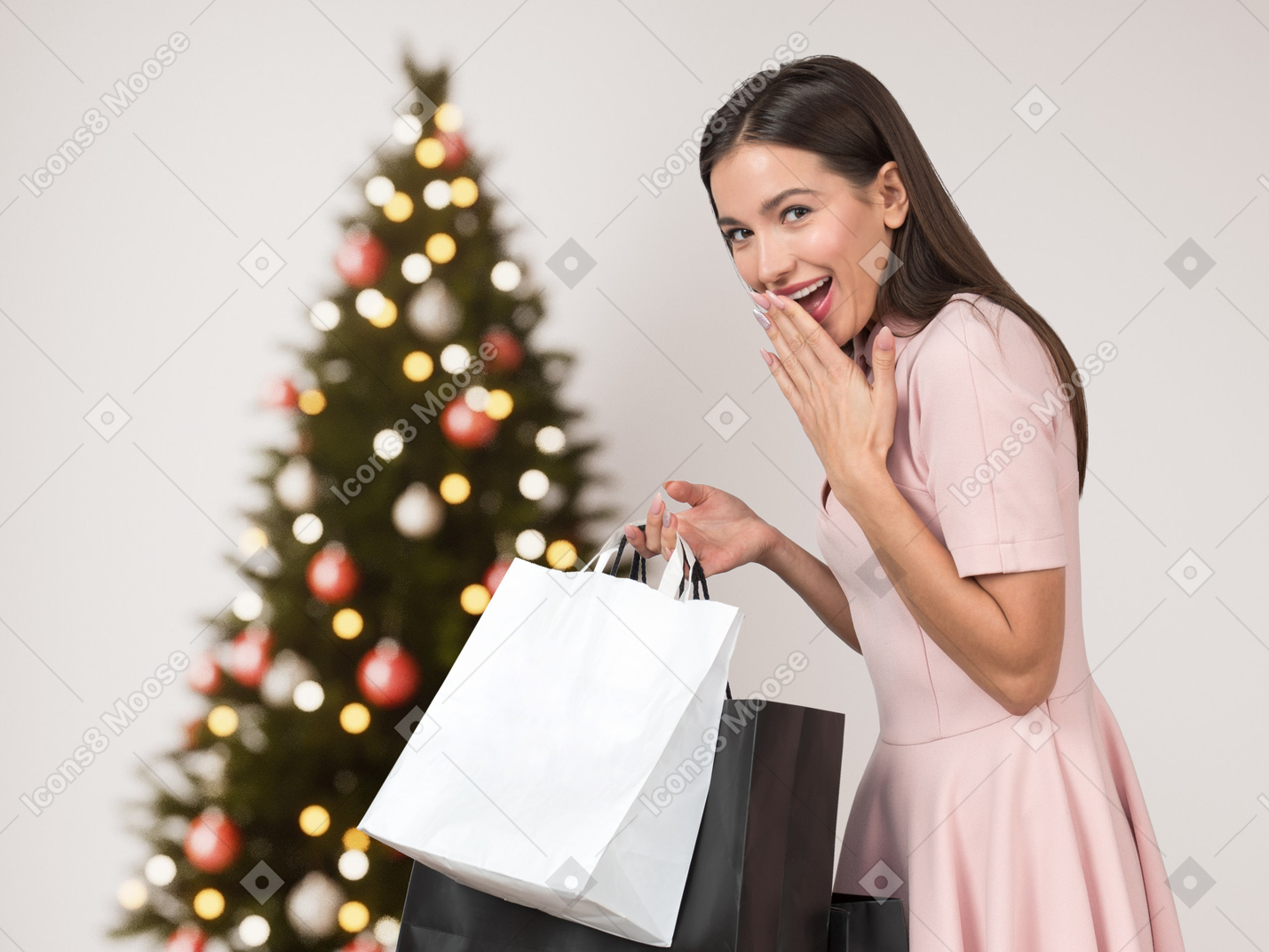 Mujer joven con bolsas de compras de pie cerca del árbol de navidad