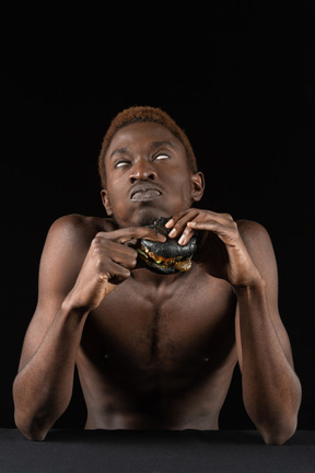 Front view of a young afro man biting a burger while rolling eyes