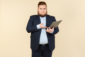 Young overweight office worker seems like not getting something and holding digital tablet