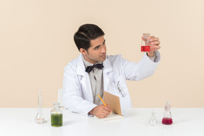 Male scientist holding bulb and sitting at the table