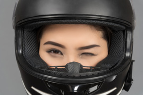 Uma jovem mulher piscando enquanto usava um capacete preto