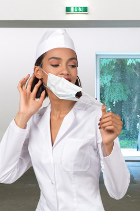 A nurse is taking off a face mask