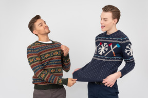 Brothers trying on knitted christmas sweaters