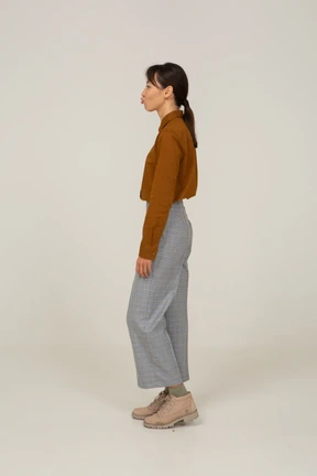 Vista lateral de un travieso puchero joven mujer asiática en calzones y blusa