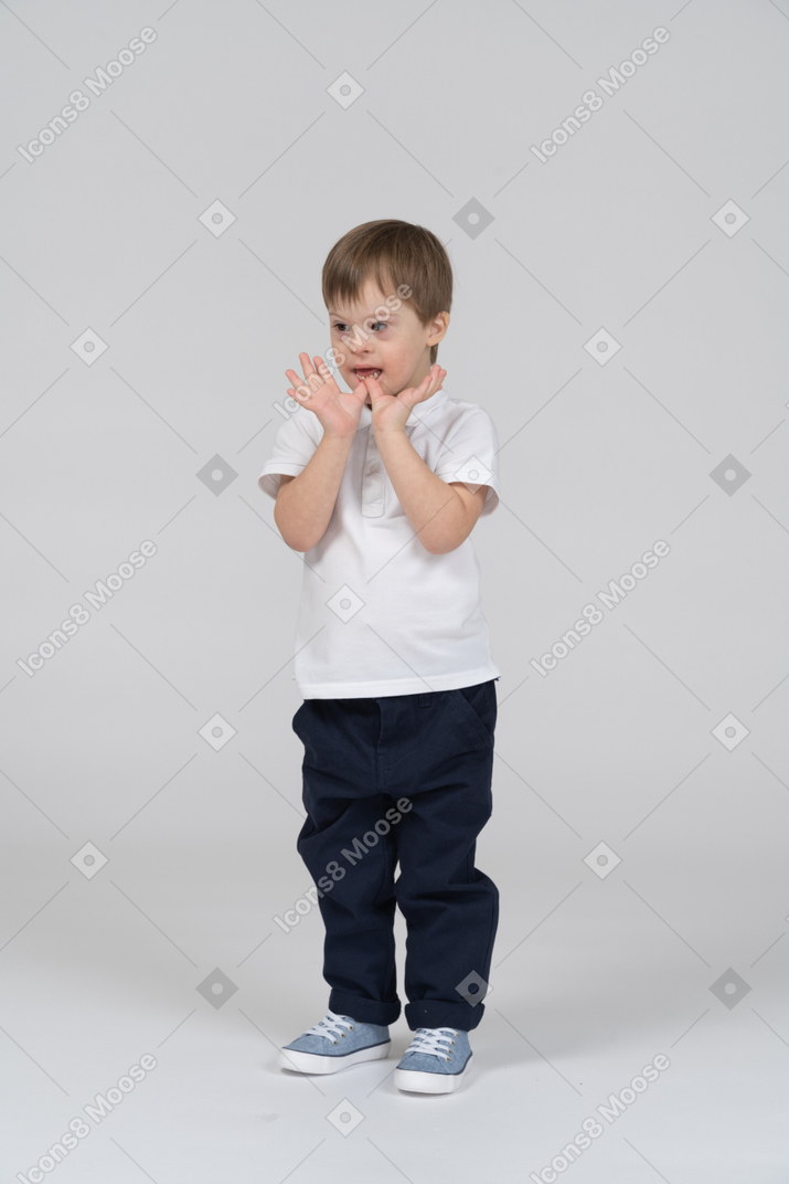 Niño pequeño tocándose las manos en la barbilla