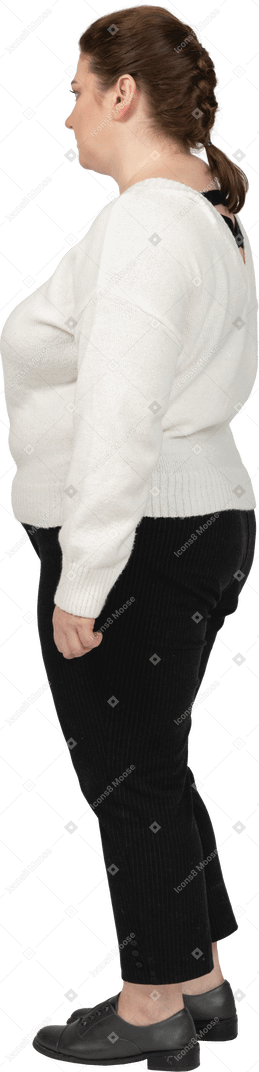 Уверенная в себе женщина больших размеров в белом свитере стоит в профиль