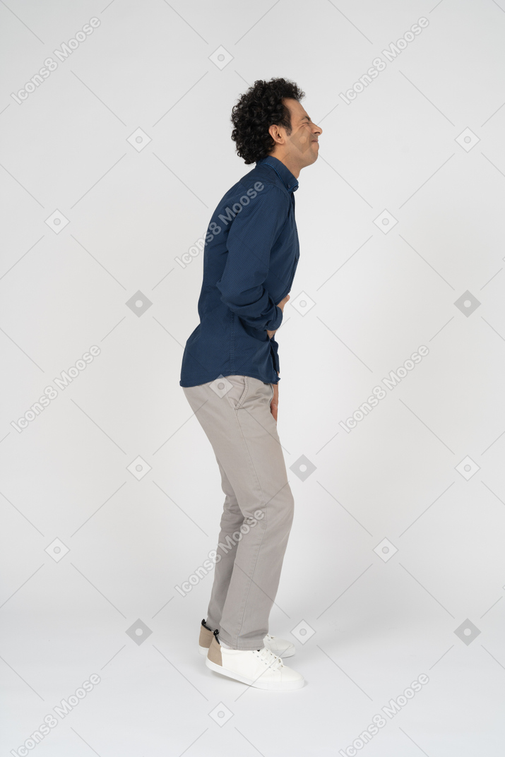 Side view of a man in casual clothes suffering from stomachache
