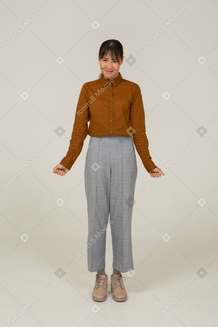 Front view of a young disappointed asian female in breeches and blouse clenching fists