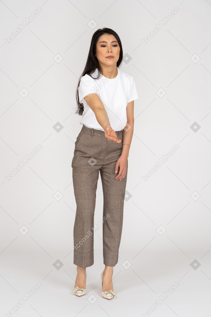 Vista frontal de uma jovem senhora de calça e camiseta esticando a mão