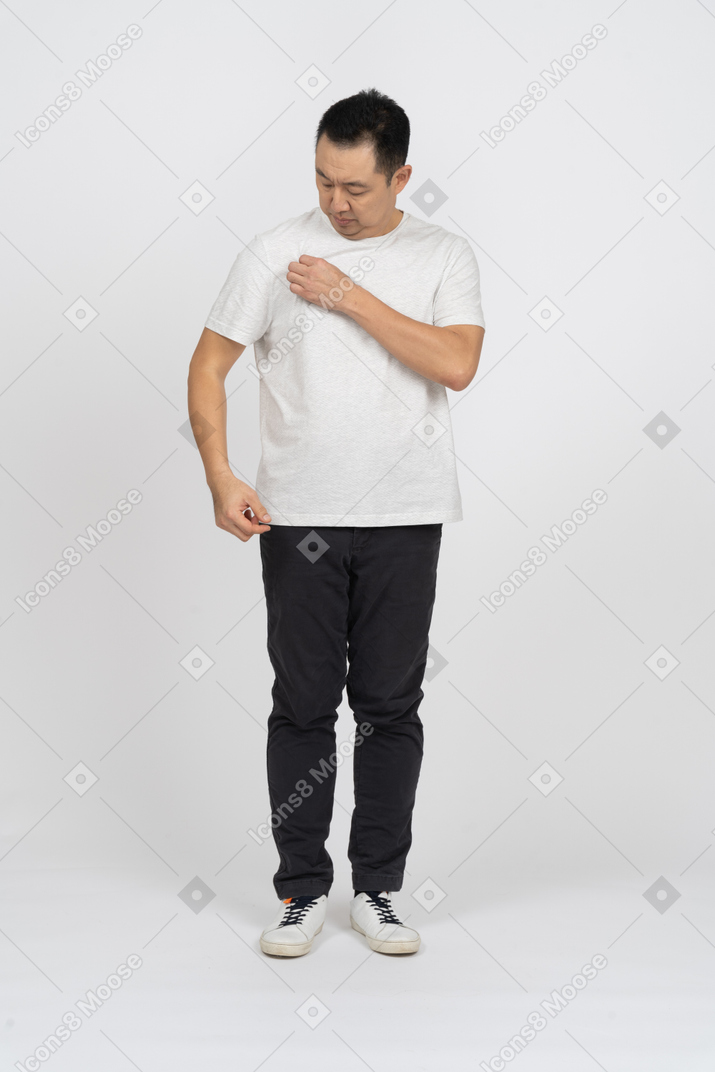 一个穿着休闲服的男人看着他的 t 恤的正面图