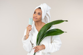 Black woman in white bathrobe and head towel enjoying her skin care routine