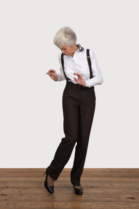 Front view of a careful old lady looking cautiously down at her leg