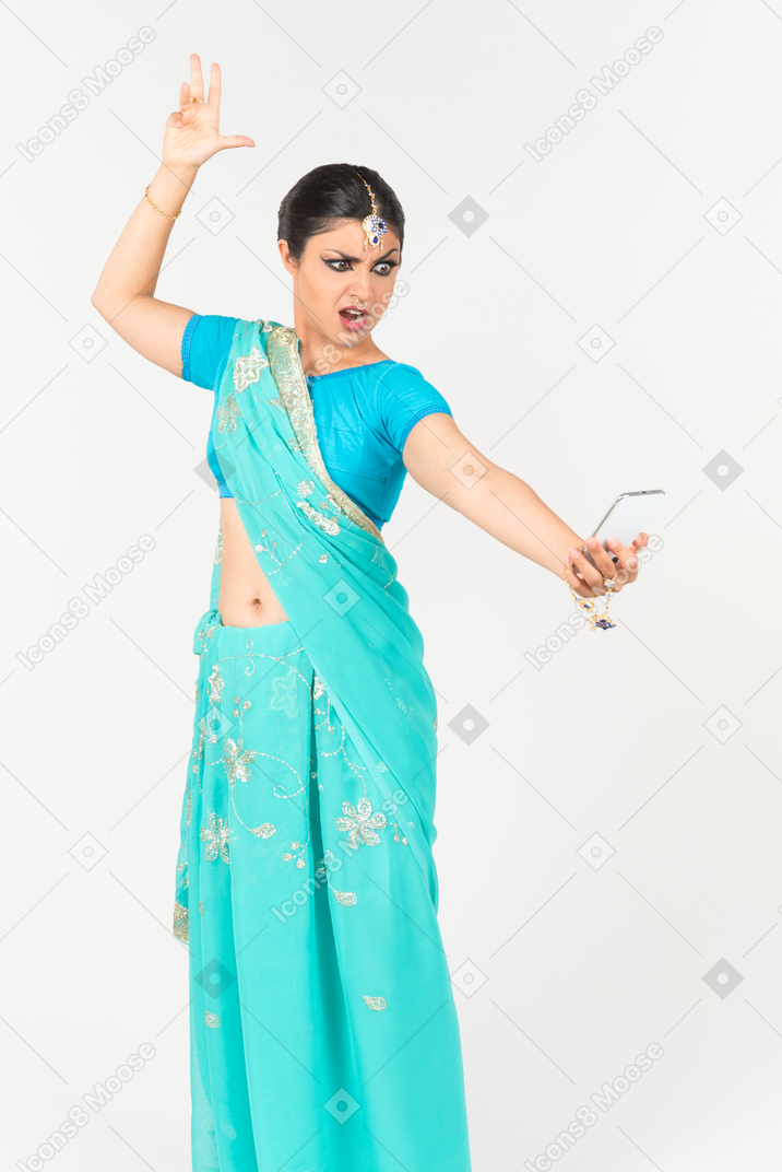 Angry looking young indian dancer looking on the phone