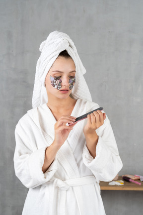 Woman in bathrobe filing her nails