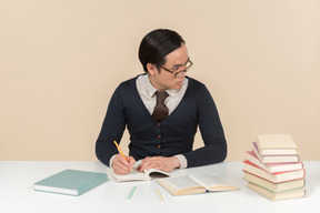 Joven estudiante asiática en un suéter escribiendo en un cuaderno