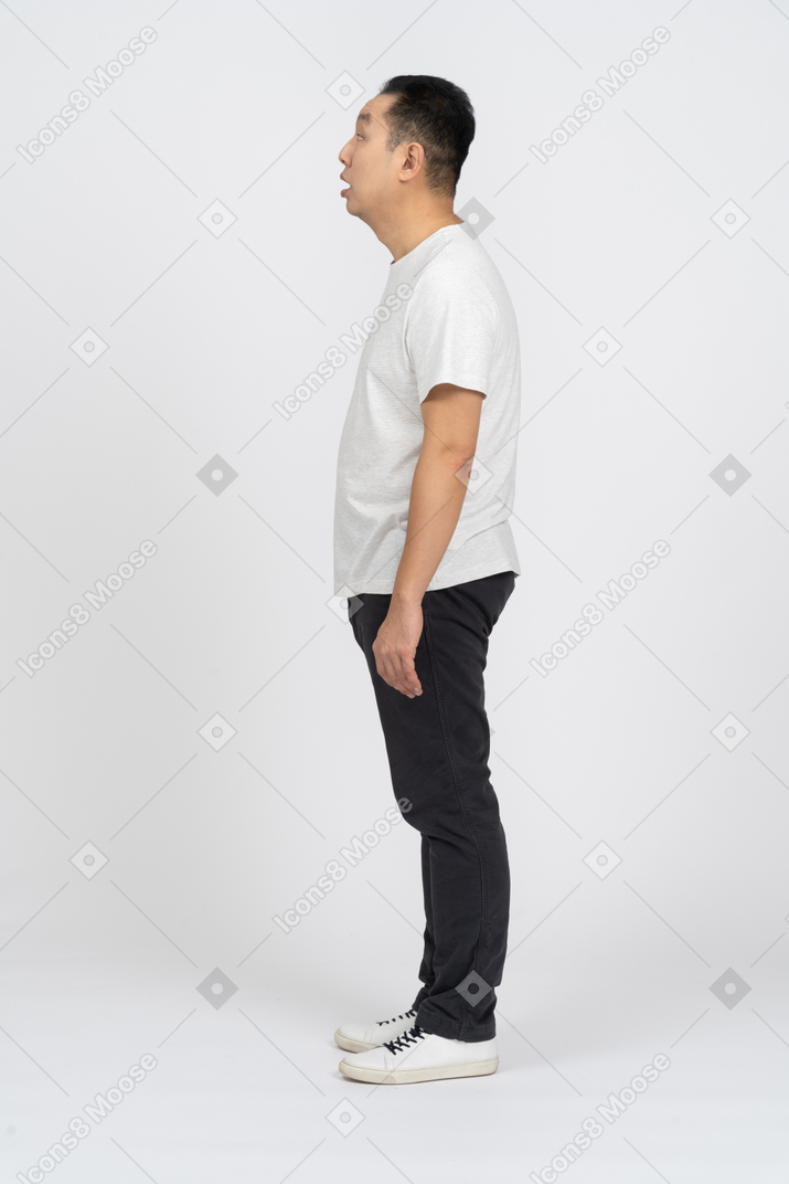 Vista lateral de um homem em roupas casuais olhando algo com interesse