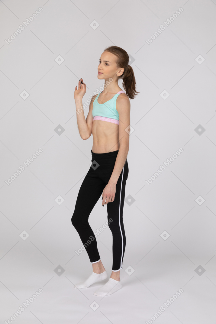Веселая девочка-подросток в спортивной одежде смотрит в сторону