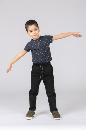 Vue de face d'un garçon mignon posant avec les bras tendus